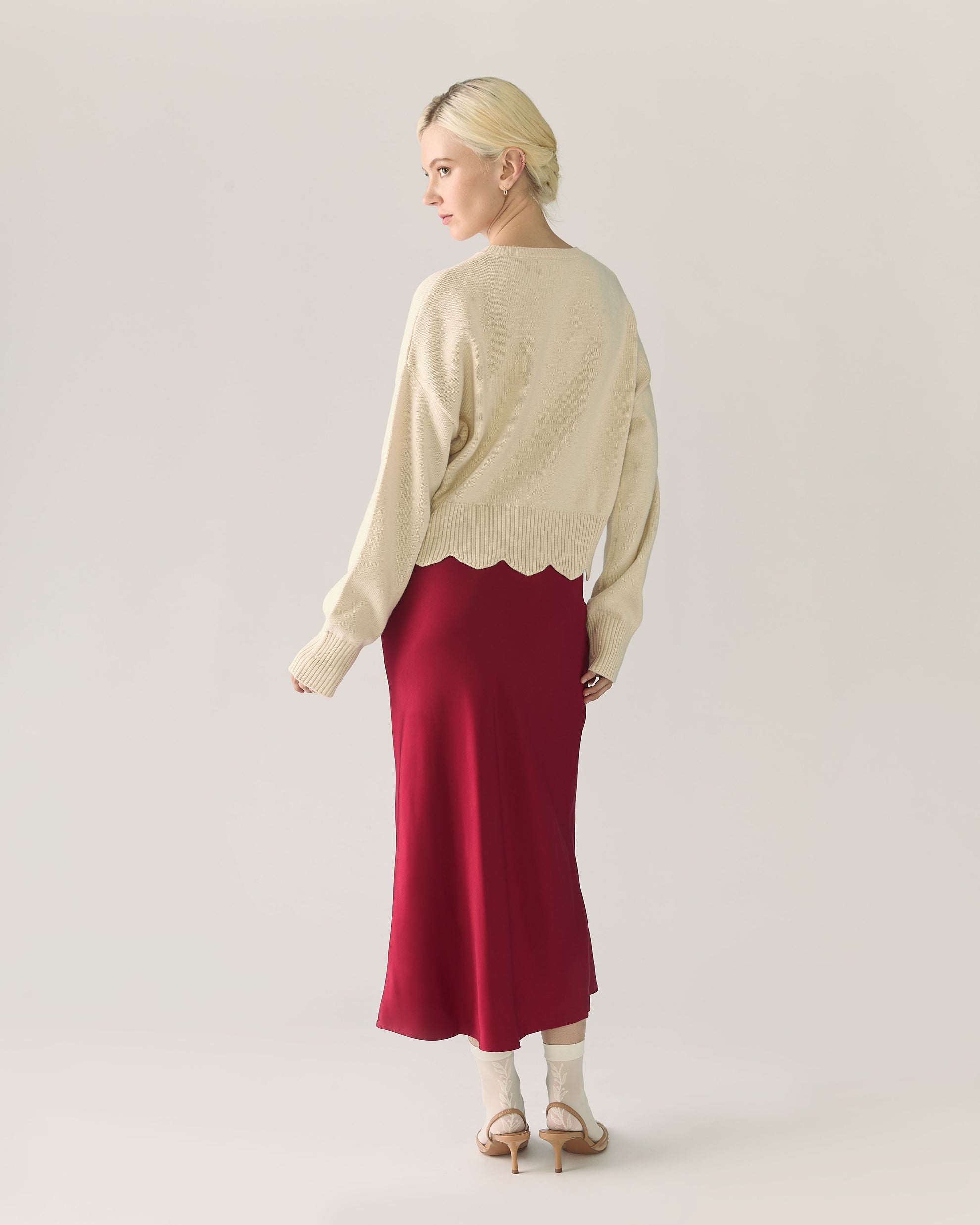 Woman wearing a beige sweater and red pomegranate skirt