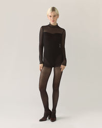 Women in black bodysuit with mesh sleeves and tights
